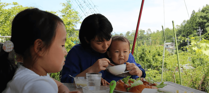 ウッドデッキでご飯を食べる親子