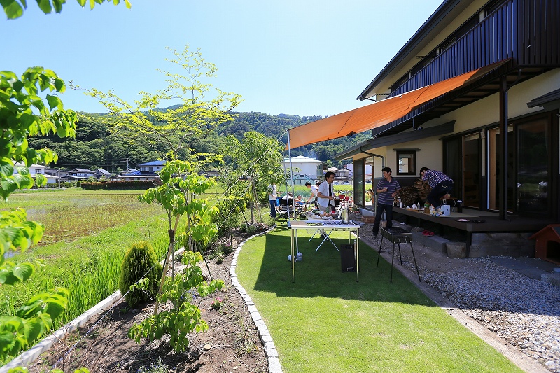 庭にタープを張ってBBQする家族